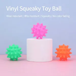 Vista detallada de pelotas de juguete para perros con púas y sonido en rosa, verde y naranja