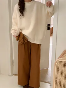 Détail d'un pull en maille blanc crème avec un pantalon marron large de style rétro