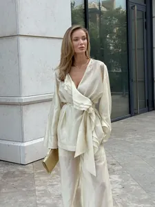 Detailed look at elegant cream Tencel ruffled wrap top and matching wide-leg trousers set