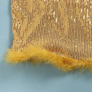 Macro view of gold sequined fabric and yellow feather trim on a sexy nightclub dress