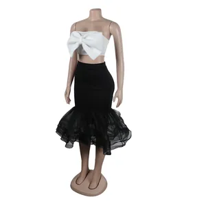 Detalle del top bandeau blanco con lazo y falda de sirena de malla negra con volantes.