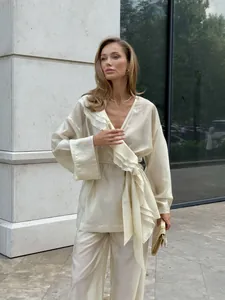 Elegant beige Tencel two-piece set featuring a ruffled wrap top and wide-leg trousers.