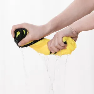 Mains essorant l'eau d'une serviette en microfibre jaune ultra-absorbante pour animaux.