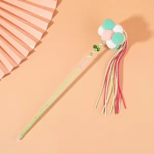 Close-up of cat teaser wand with pastel pom-poms and colorful tassels (82 chars)