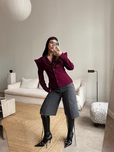 Vista completa di un blazer bordeaux con spalline a punta e pantaloncini grigi chic.