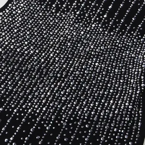 Primo piano di strass argentati disposti in linee diagonali su un abito aderente nero.