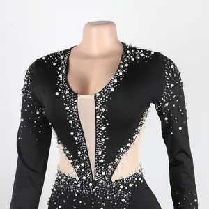 Primo piano di una tuta in rete nera con eleganti perle e dettagli in strass.