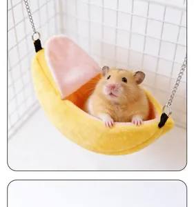 Hamac douillet en peluche en forme de banane pour hamster suspendu dans une cage blanche