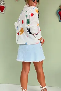 Side view of a white long-sleeve button-up blouse with vibrant star patterns