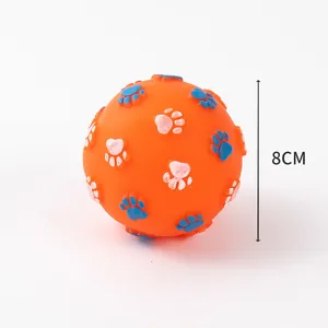 Vue détaillée d'une balle sonore de 8 cm pour chien orange avec motifs de pattes bleues