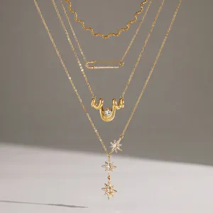 Gros plan de colliers multicouches en acier doré avec pendentifs étoile et épingle