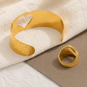 Détail d'un ensemble bracelet manchette et bague en acier doré 18 carats au motif cœur martelé.