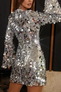 Vista detallada de la textura de lentejuelas plateadas brillantes en este vestido corto