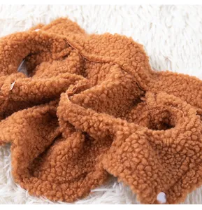 Gros plan détaillé sur la texture douce en polaire sherpa marron d'un gilet chaud pour chien