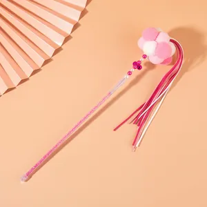 Detail view of a fairy-style cat teaser wand with pink pom-poms and glitter handle.