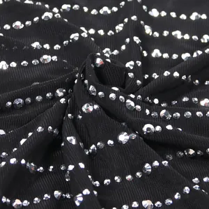 Dettaglio in primo piano del tessuto a rete nera trasparente con strass argento scintillanti.