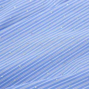 Gros plan de tissu à rayures bleues et blanches orné de brillants strass étincelants