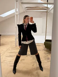 Selfie allo specchio con un blazer scuro strutturato con spalline a punta ed elegante.