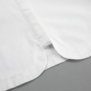 Dettaglio macro dello spacco laterale e delle cuciture fini su una camicia di cotone bianco.