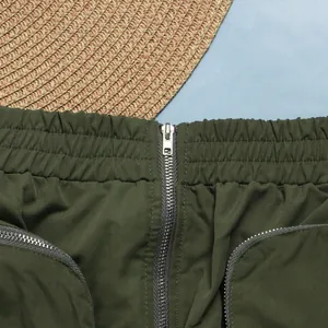 Detailed close-up of an olive green cargo mini skirt with functional metal zippers