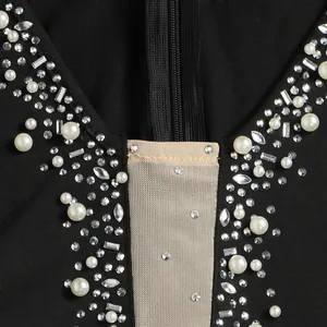 Primo piano di strass e perle su una tuta nera sexy con inserto in rete trasparente.