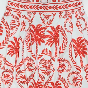 Gros plan d'un imprimé palmier et feuilles rouges sur tissu blanc pour combinaison femme