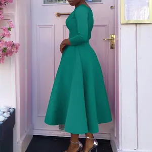 Seitenansicht eines eleganten smaragdgrünen Abendkleides vor einer rosa Tür im Hintergrund