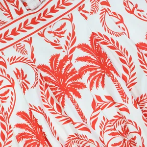 Vue détaillée de l'imprimé palmier tropical rouge vif sur le tissu d'une combinaison blanche