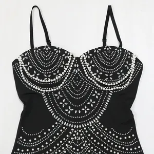 Macro view of black evening dress featuring intricate rhinestone and pearl embellishments.