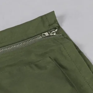 Close-up of silver metal zipper and pocket detail on olive green cargo mini skirt.