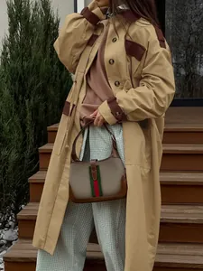 British retro khaki long trench coat styled with a vintage striped hobo handbag