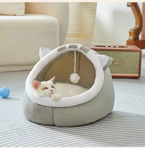 Cama para gatos de felpa gris y blanca semicerrada con bola de juguete colgante en el hogar.