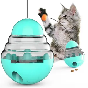 Jouet distributeur de friandises turquoise pour chat avec un chat curieux sur fond blanc