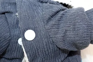 Macro view of blue ribbed fabric and white button on a thickened dog winter coat
