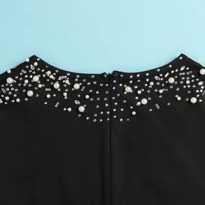 Primo piano di strass e perle sintetiche sullo scollo di una tuta intera nera elegante.