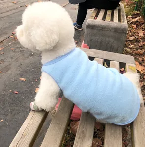 Gros plan d'un petit chien blanc portant un gilet d'hiver en polaire bleu clair confortable