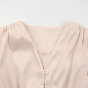 Detail van een elegante satijnen jurk in Franse stijl met een V-hals en knoopjes