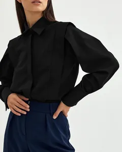 Detail view of black cotton shirt with structured shoulders and puffed sleeves