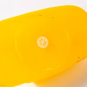 Detailed macro view of the white squeaker mechanism on a durable yellow vinyl dog chew toy