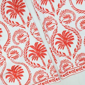 Gros plan sur l'imprimé palmier et feuilles rouge vif sur le tissu blanc d'une combinaison.