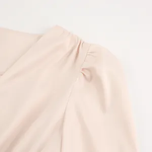 Detailweergave van de geplooide schouder en pofmouw van een elegante lichtroze satijnen jurk