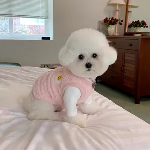 Adorable Bichon Frisé blanc portant un gilet en polaire rose et un t-shirt blanc au chaud