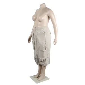 Detailed view of beige cargo midi skirt featuring multiple zippers and utility pockets.