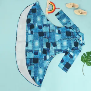 Blue denim-print dress laid flat with rainbow decor and beige loafers on blue background.