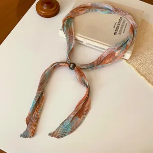 Macro view of retro pleated printed necktie necklace with decorative bead detail.
