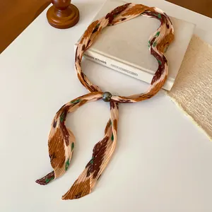 Close-up of retro pleated printed scarf necklace with elegant grey pearl slider