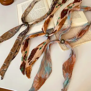 Close-up of pleated printed neck scarves with bead accents on an open book.