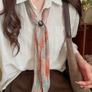 Close-up of pleated print necktie accessory with decorative bead on a white shirt