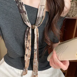 Detail of a vintage pleated printed scarf necklace with a decorative brown bead.