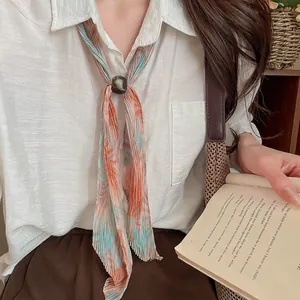 Close-up of retro pleated printed scarf necklace with marble bead closure on white shirt